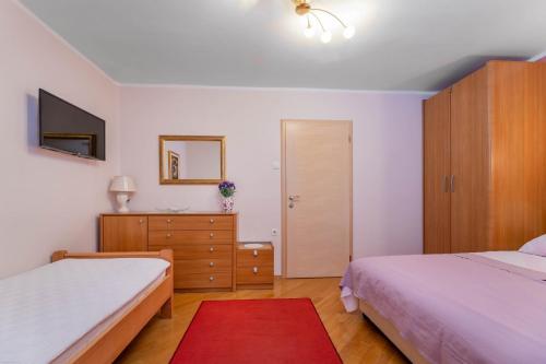 a bedroom with two beds and a dresser and a mirror at Rooms Nadica in Baška