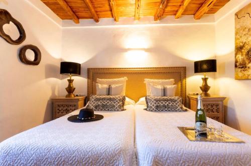 a bedroom with two beds with a bottle of wine at Can Pep Den Sitges in Sant Joan de Labritja