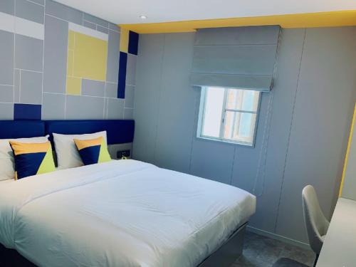 a bedroom with a white bed with blue walls and a window at 7 Days Inn Guangzhou Zoo Huanghuagang Metro Station in Guangzhou