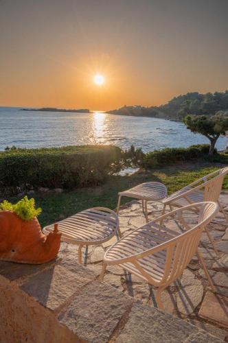 three chairs and a table with the sunset in the background at Casa del mare in Pýrgos