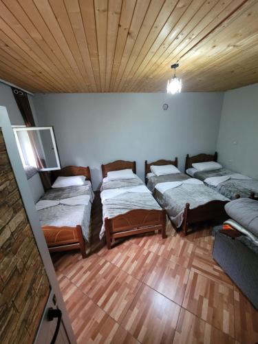 a room with four beds in it with a wooden ceiling at Guest House Emanueli in Tropojë