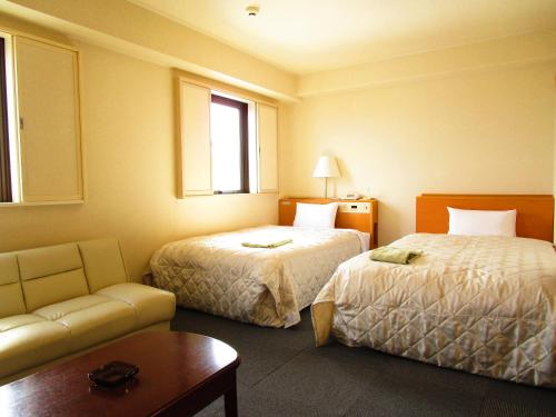 a hotel room with two beds and a couch at Green Hotel Omagari in Daisen
