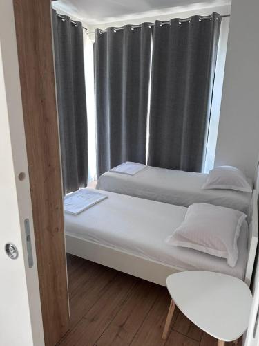 two beds in a room with a window at Brean apartment in Vlorë