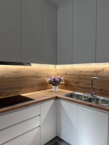 a kitchen with white cabinets and a sink and flowers at Brean apartment in Vlorë