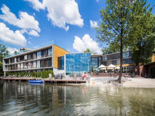 ein Gebäude mit Glasfassade neben einem Wasserkörper in der Unterkunft Przystań Hotel&Spa in Olsztyn