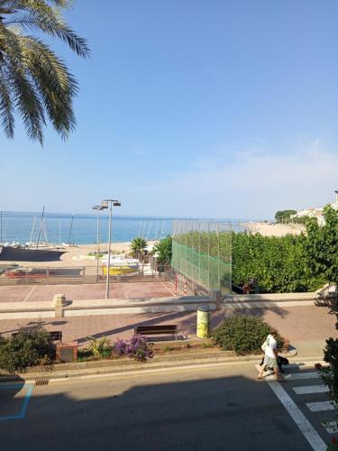dos personas caminando por una calle cerca de la playa en Beachfront Apartment with Sea Views & Private Parking, en Sant Pol de Mar