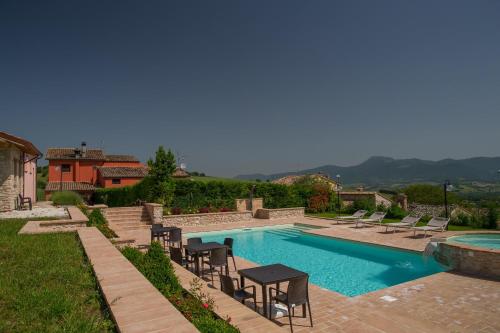 a swimming pool with chairs and a table in a yard at Il Casato in Castelraimondo