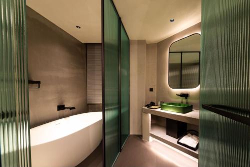 a bathroom with a tub and a sink and a mirror at 茑岛海景潮宿NiaoDao Seaview Hotel in Xiamen