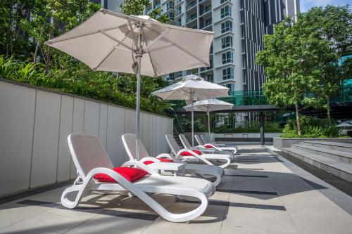 a row of lounge chairs and an umbrella at The Shore Hotel & Residences in Melaka