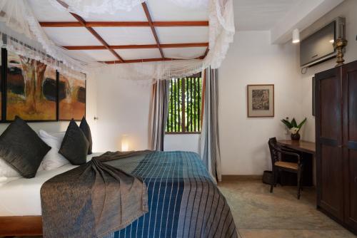 a bedroom with a bed and a desk and a window at Cinnamon Museum Mirissa in Mirissa