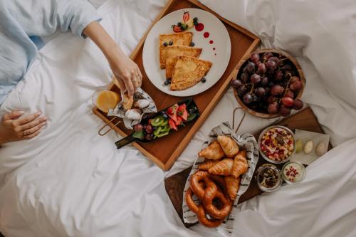a person laying in bed with a tray of food at Mövenpick Resort & Spa Karpacz in Karpacz