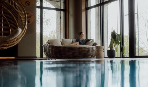a woman sitting on a couch in a living room with a pool at Mövenpick Resort & Spa Karpacz in Karpacz