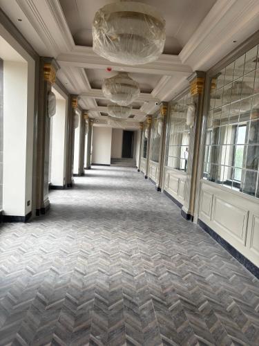 an empty hallway in a building with a chandelier at The Supreme Hotel and Banquet in Gaya
