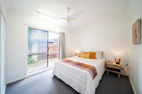a white bedroom with a bed and a large window at Townsville Family Getaway in Townsville
