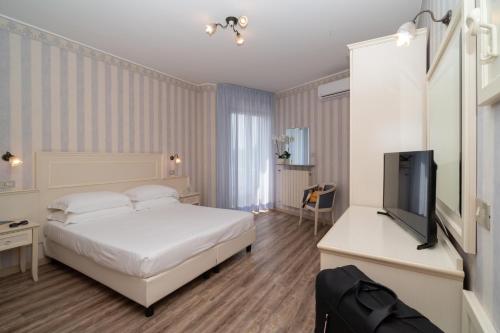 a bedroom with a bed and a flat screen tv at Hotel Riviera in Porto San Giorgio