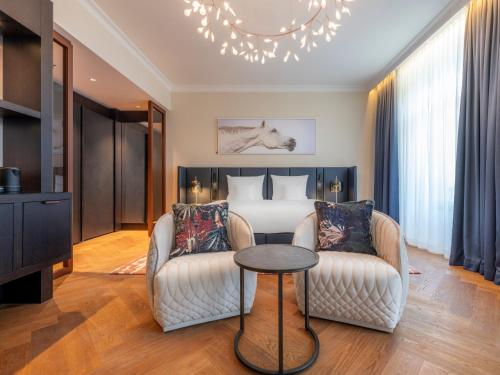 a hotel room with two chairs and a bed at Steigenberger Icon Europäischer Hof Baden Baden in Baden-Baden
