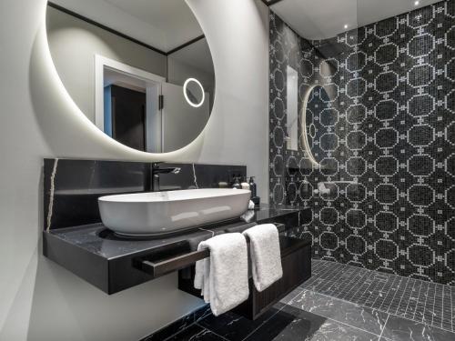 a bathroom with a sink and a mirror at Steigenberger Icon Europäischer Hof Baden Baden in Baden-Baden