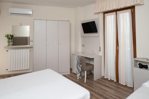 a bedroom with a bed and a desk with a computer at Hotel Riviera in Porto San Giorgio