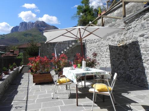 a table and chairs with an umbrella on a patio at Agriturismo La Calamaia in Gorfigliano