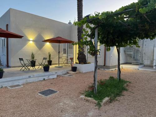 马尔萨拉Stagnone Sunset Holidays的房屋设有带桌子和遮阳伞的庭院