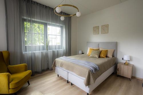 een slaapkamer met een bed en een gele stoel bij Sun Side Apartments Pärnu in Pärnu