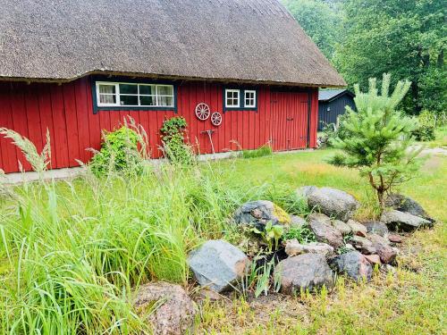 a red barn with rocks in front of it at Niiduliiva Holiday Home in Nasva