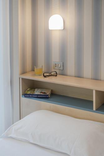 a room with a bed and a shelf with glasses at Hotel Riviera in Porto San Giorgio