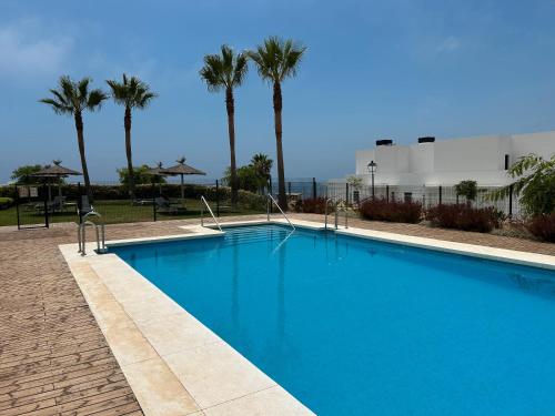 Una piscina azul con palmeras al fondo. en Chulera Beach townhouse sea views, en Manilva