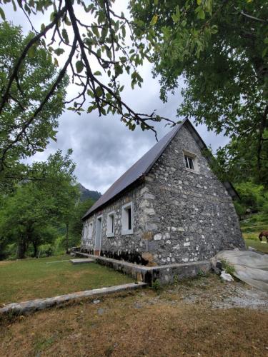 an old stone house with a gambrel roof at Guest House Emanueli in Tropojë