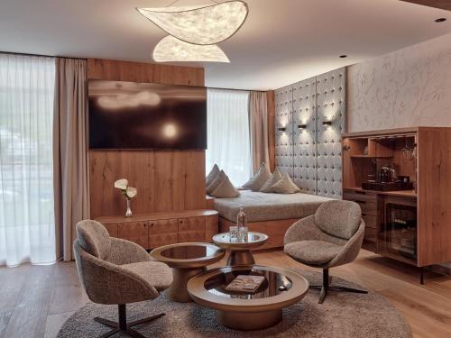 a hotel room with a bed and two chairs and a table at DAS EDELWEISS - Salzburg Mountain Resort in Grossarl