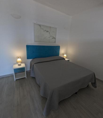 a bedroom with a bed with a blue headboard and two lamps at B&b Ranieri in Le Castella