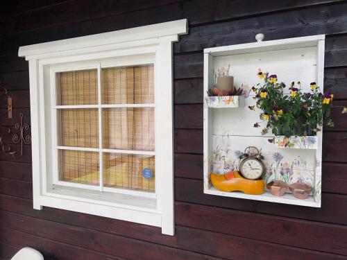 two windows on a wall with plants and a clock at Niiduliiva Holiday Home in Nasva