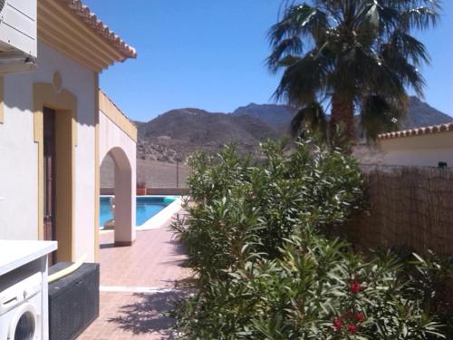 a house with a swimming pool and a palm tree at Casa Panorama in Mazarrón