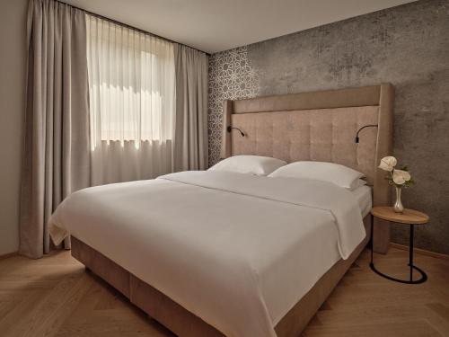 a bedroom with a large white bed and a window at DAS EDELWEISS - Salzburg Mountain Resort in Grossarl