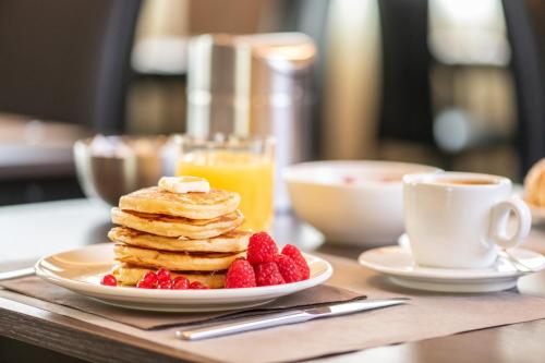 a plate of pancakes with berries and a cup of coffee at Hotel Palace Verona in Verona
