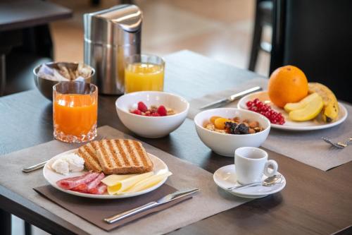a breakfast table with plates of breakfast foods and orange juice at Hotel Palace Verona in Verona