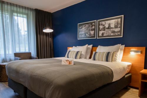 a bedroom with a large bed with blue walls at Landgoed Mennorode in Elspeet