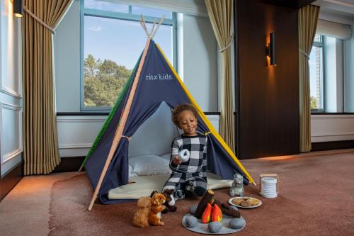 a young boy sitting in a tent with stuffed animals at The Ritz-Carlton New York, Central Park in New York
