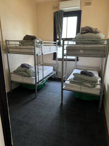 a room with three bunk beds and a window at Emu Backpackers Perth - note - Valid Passport required for check in in Perth