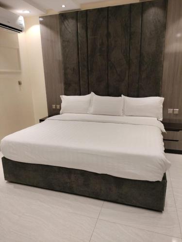a bedroom with a large bed with white sheets and pillows at فلل الكناري in Taif
