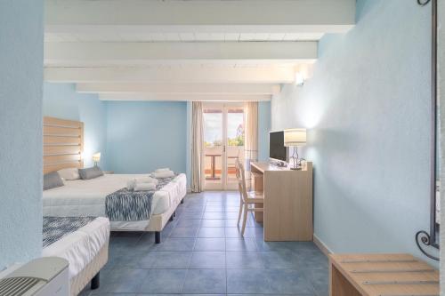 a hotel room with two beds and a table and a desk at Hotel La Caletta Village in La Caletta