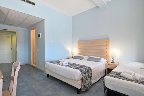 a bedroom with two beds and a table and chairs at Hotel La Caletta Village in La Caletta