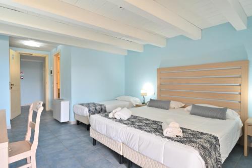 two beds in a room with blue walls at Hotel La Caletta Village in La Caletta