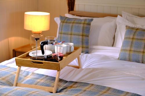 a bed with a table with cups and a lamp on it at Otter Cottage in Inverness
