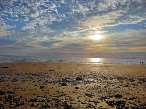 a sandy beach with the sun setting on the water at CABIN 8 Pet friendly Family glamping Seaview in Llwyngwril