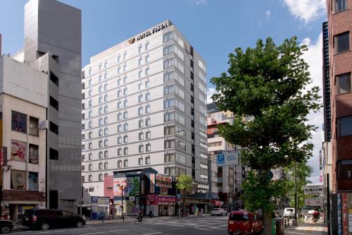 a tall white building on a city street at Hotel Vista Osaka Namba in Osaka