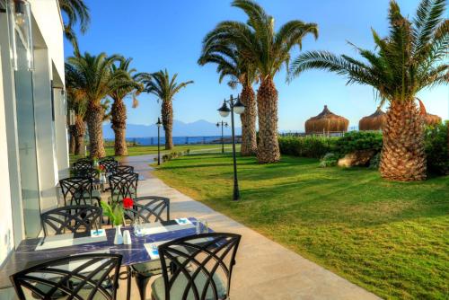 a patio with tables and chairs and palm trees at Le Bleu Hotel & Resort Kusadasi in Kusadası
