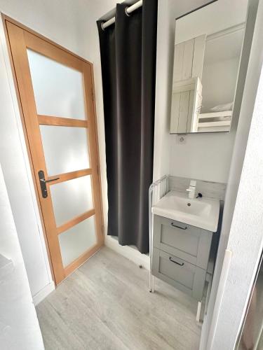 La salle de bains est pourvue d'un lavabo, d'un miroir et d'une porte. dans l'établissement Studio pour 2 personnes à 100m de la plage, à Berck-sur-Mer