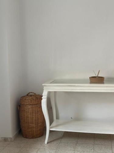 a white console table with a basket next to it at Dar Aïcha 