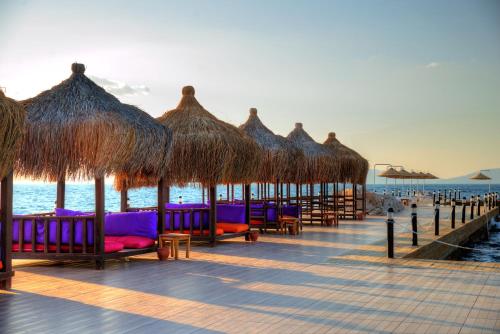 a row of chairs and straw umbrellas on a beach at Le Bleu Hotel & Resort Kusadasi in Kusadası